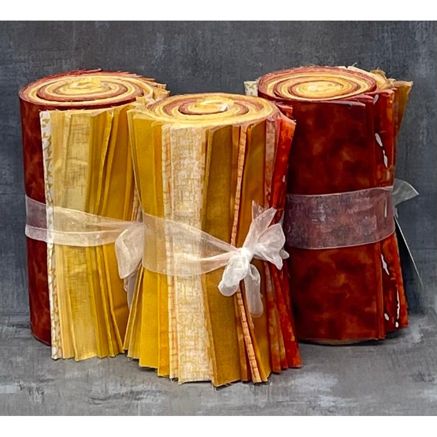 Three rolls of fabric in red, orange, and yellow with ribbons on a textured gray background