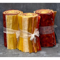 Three rolls of fabric in red, orange, and yellow with ribbons on a textured gray background