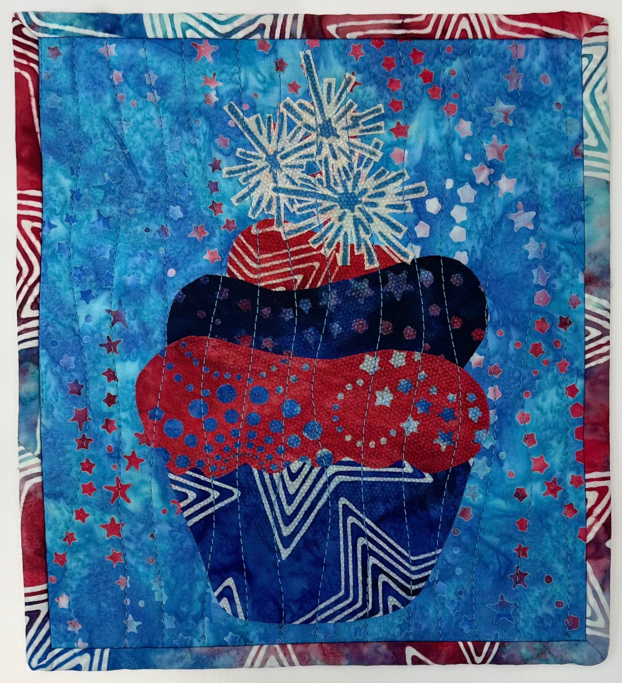 Quilt with a bear wearing a hat and scarf against a blue background with stars and fireworks.