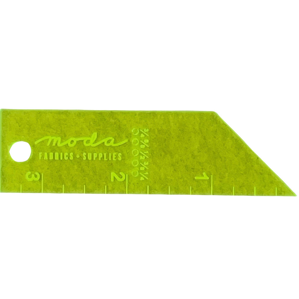 A lime green fabric yardage cutter from Moda Fabrics & Supplies, featuring a triangular shape with measurement markings and a circular hole on the left side, shown on a plain white background.